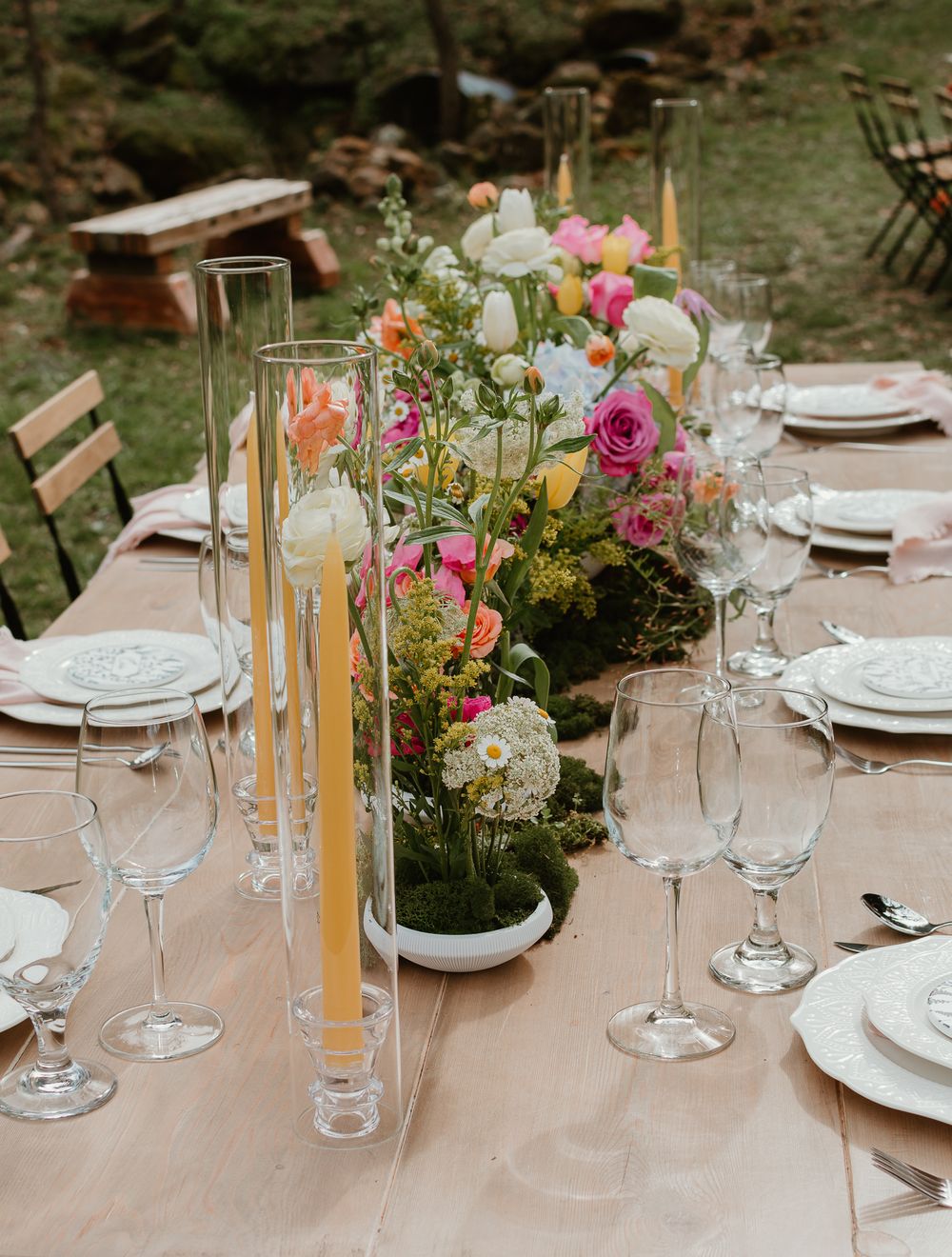Elegant table setting with pink and white floral centerpieces and gold candle holders.