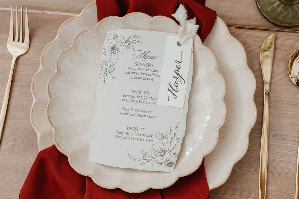 Wedding menu cards with scalloped edges and floral designs displayed on wooden table.
