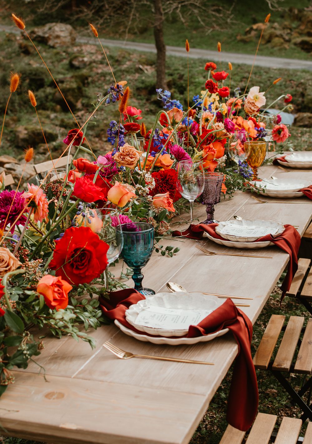 Rustic outdoor table settings with bright floral arrangements and white place cards.