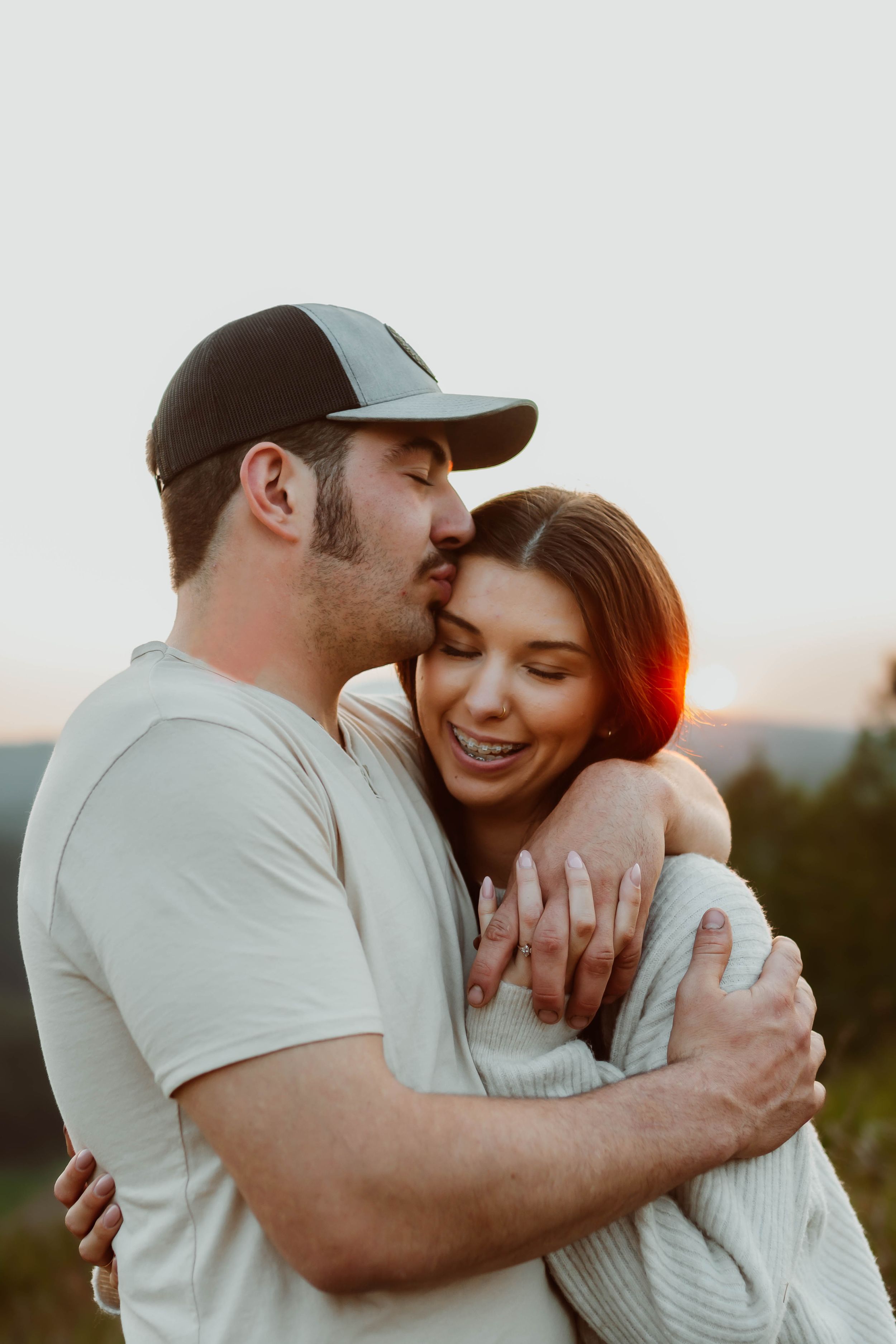 Romantic sunset engagement photos show couple laughing and embracing outdoors.