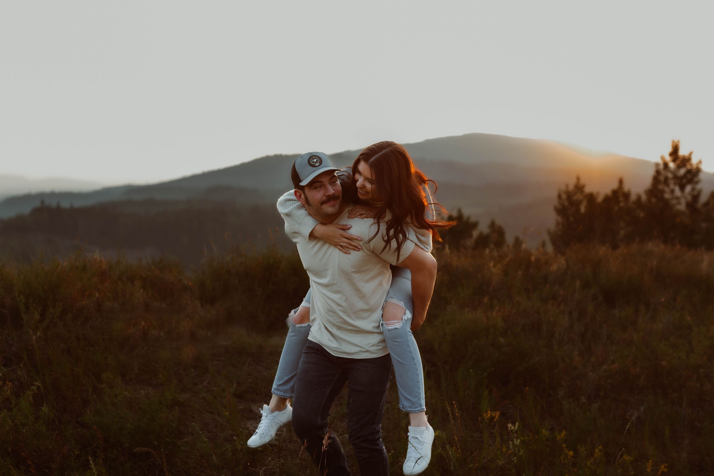 Couple shares intimate moment against mountain backdrop at sunset.