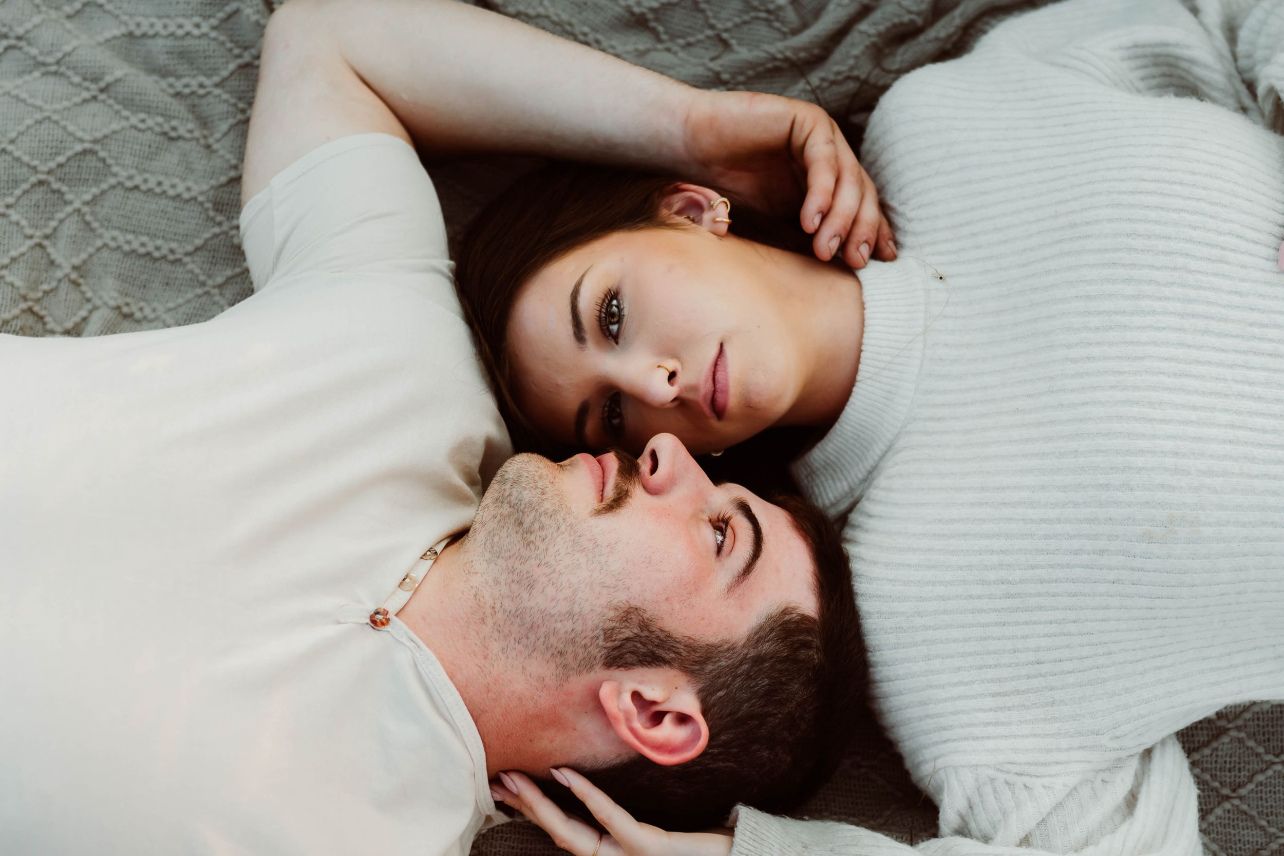 Intimate close-up photo of couple lying down together in casual attire.