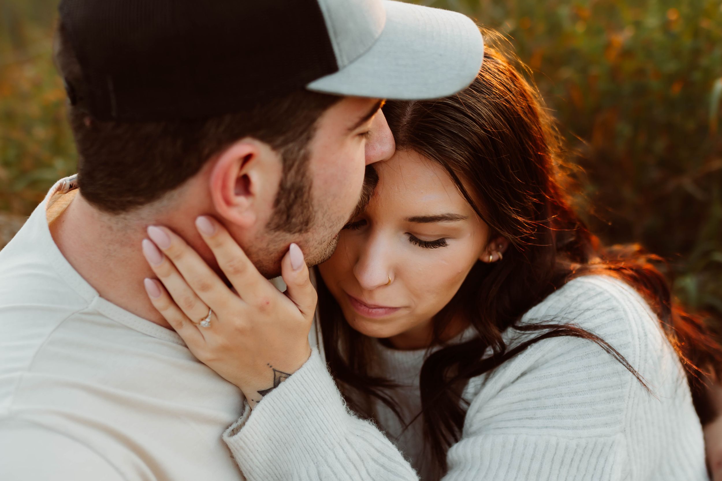 Couple shares tender moment during outdoor fall engagement photo session.