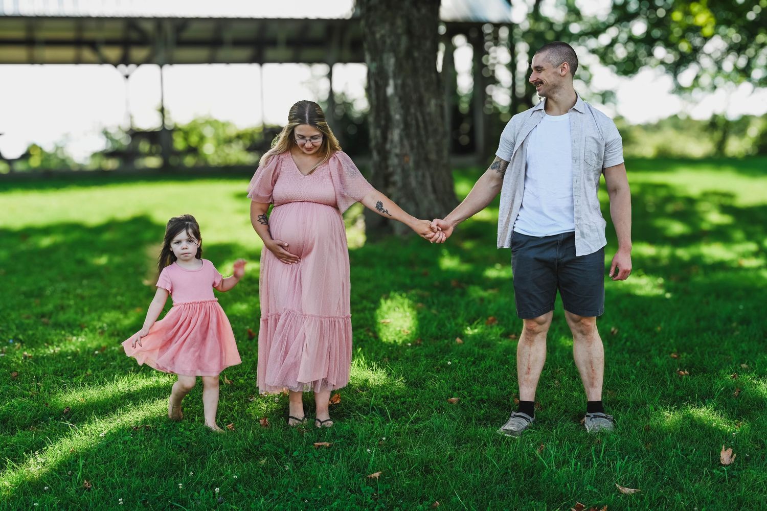 mom, dad, daughter walk and hold hands during maternity photo shoot with K. Manchuck Photography in Hudson, NY