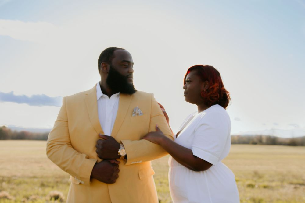 Couple in formal attire sharing intimate moment in golden field at sunset.