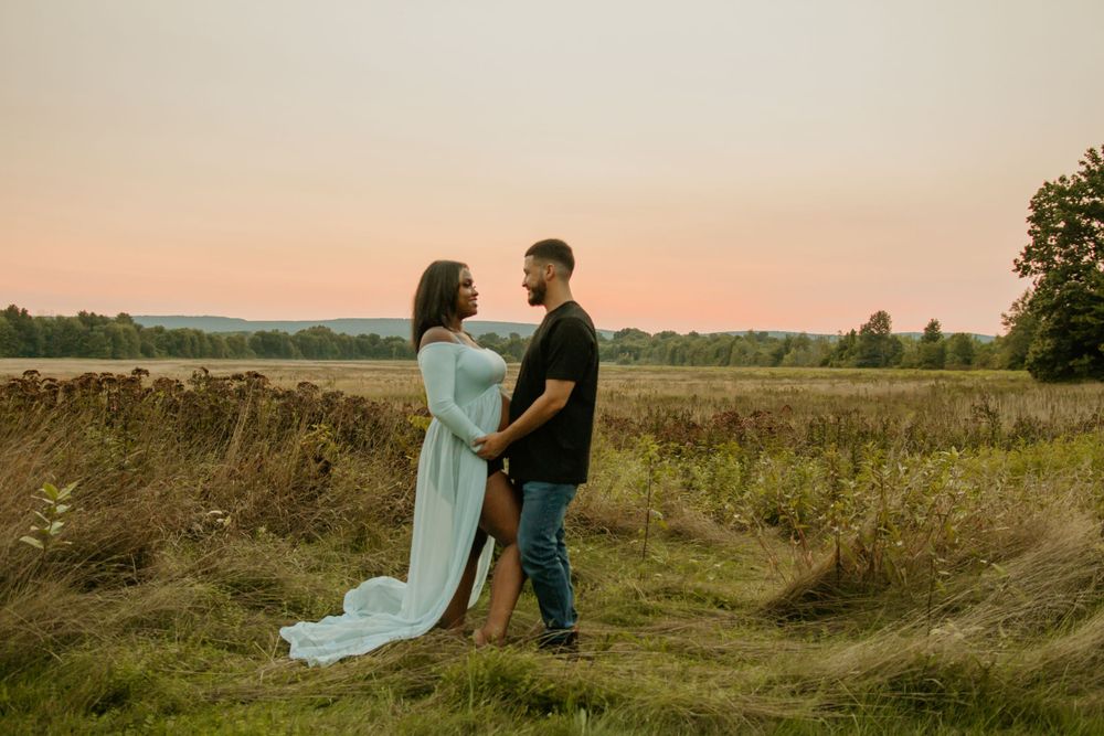 Couple embracing in flowing dress and casual wear during golden hour in a rural field.
