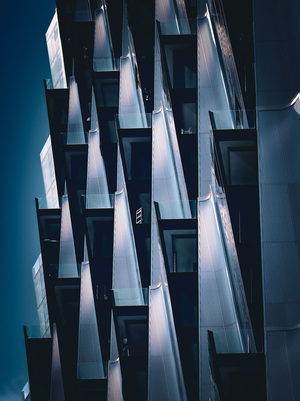 Modern geometric architecture with sharp angular balconies creating dramatic shadows.