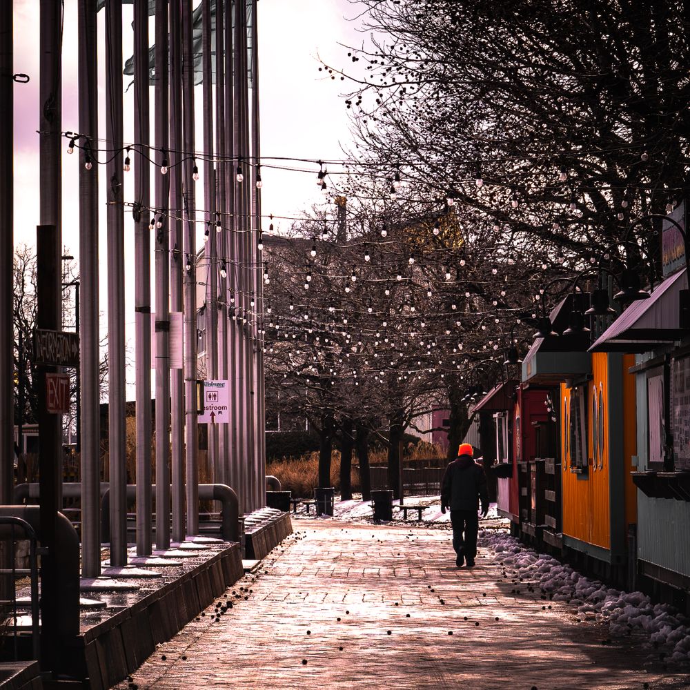 Winter street scene with string lights and metal columns creating dramatic urban atmosphere.