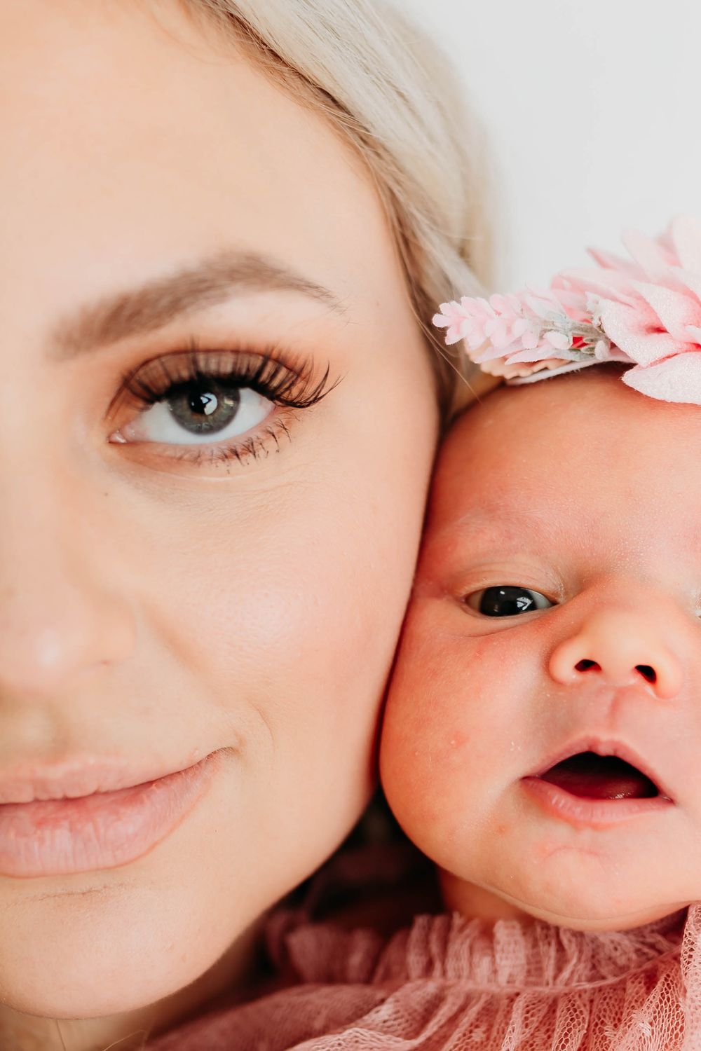 Close up portrait showing intimate mother-child moment with pink floral accent.