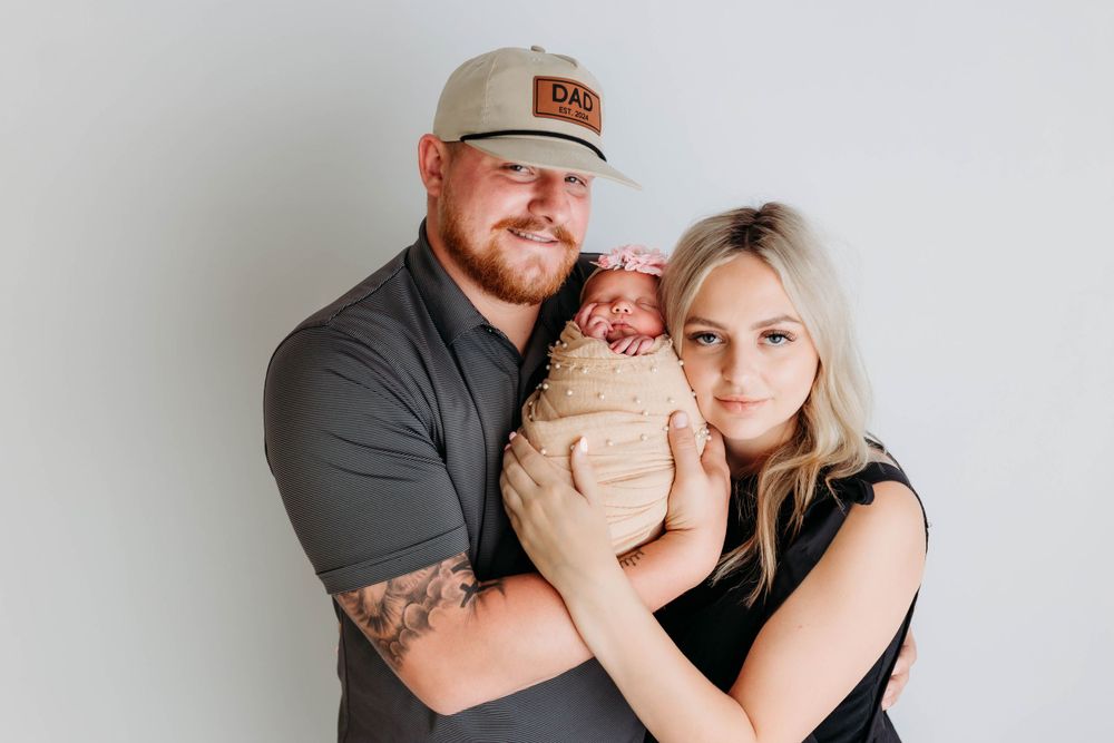 Family portrait against white wall features intimate moment with newborn.