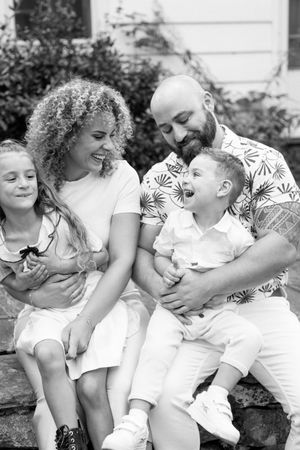 A joyful family shares laughter while sitting together outdoors in black and white photography.