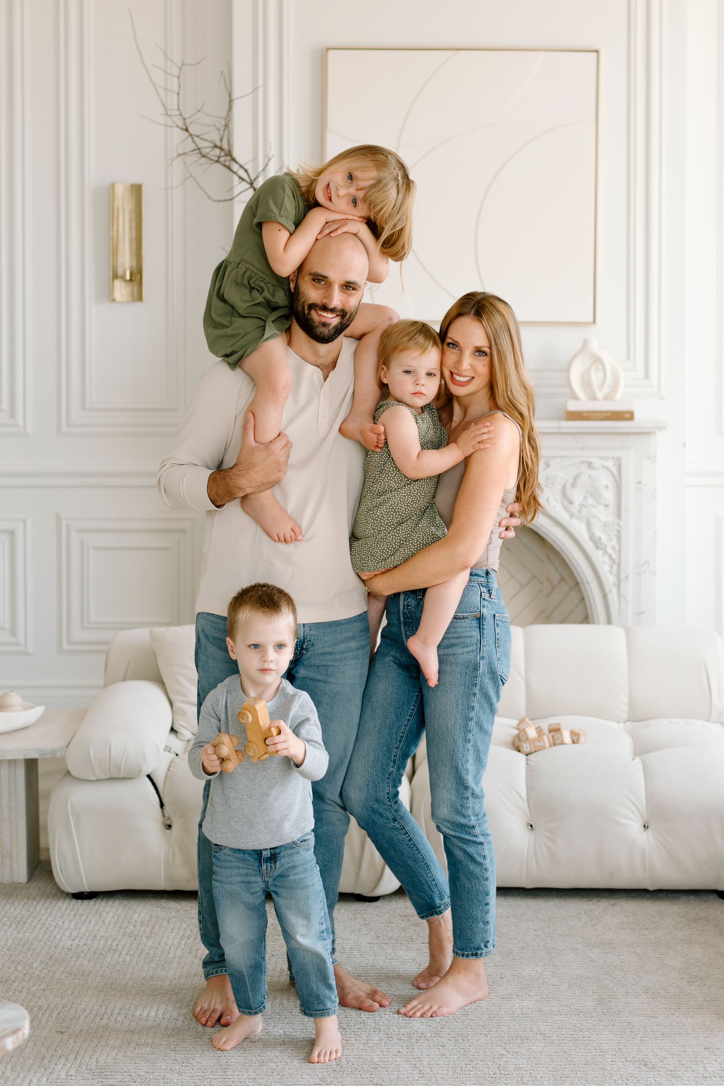 A family shares joyful moments together in a bright white room with decorative wall moldings.