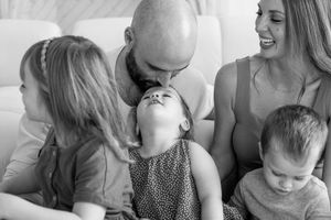 A black and white candid family moment showing joyful laughter and connection while sitting together on a couch.