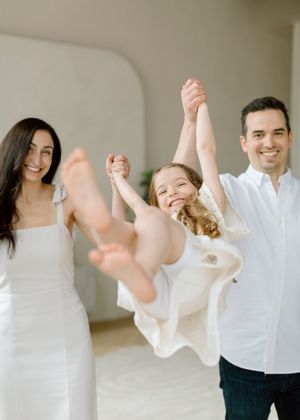 A group of people in white outfits dance and celebrate together in a bright indoor space.