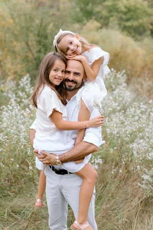 Sweet couple embracing in a wildflower meadow wearing white outfits during sunset outdoor photo session.