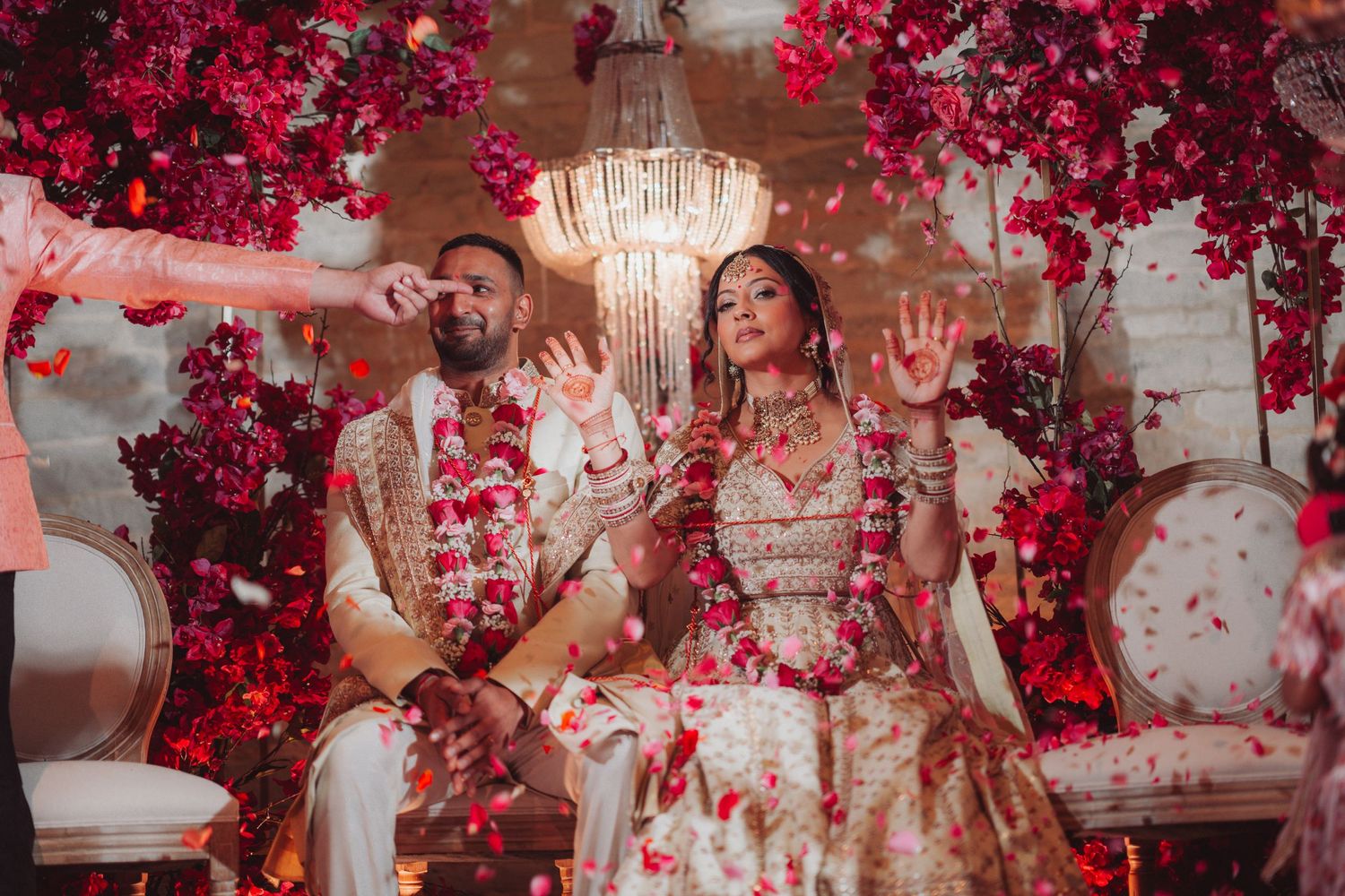 Celebratory moment under a red floral chandelier during an elegant wedding reception.
