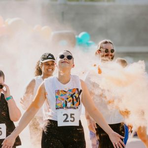 Color Run 5K event participant smiles after passing finish line.