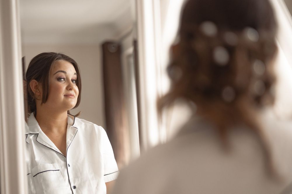 Nurse in white uniform gazing thoughtfully while standing in a softly lit hospital hallway.