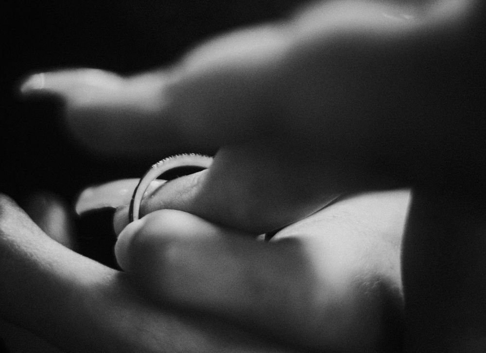 Close up artistic black and white photograph of wedding rings creating soft shadows.
