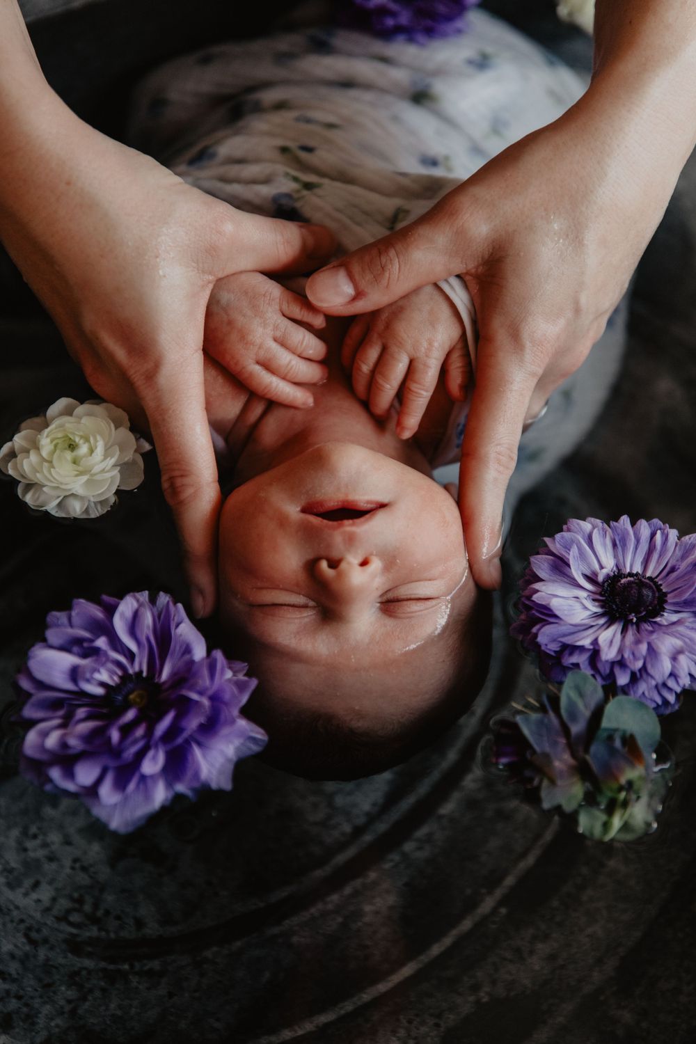 Un nouveau-né endormi dans un bain fleuri entouré de délicates fleurs de roses blanches repose doucement dans les mains.