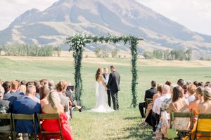 A scenic outdoor wedding ceremony with mountain views and guests seated on wooden benches in a grassy field. Lake Tahoe wedding photographer