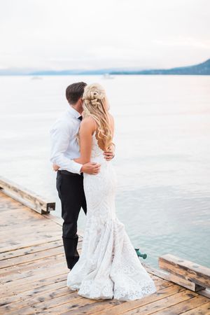A couple embraces on a wooden dock overlooking serene waters and mountains during wedding at Hyatt Regency in Lake Tahoe.