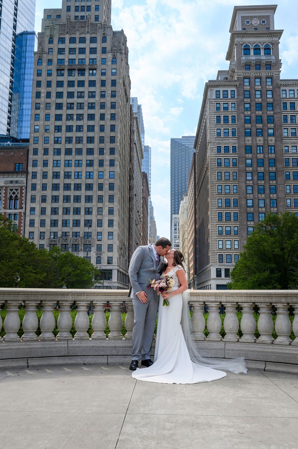 A couple shares a romantic moment on a balcony overlooking Chicago's iconic skyscrapers and urban architecture.