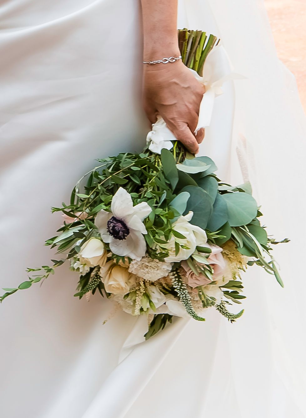 A wedding bouquet of white anemone flowers and eucalyptus leaves shown from different angles on a white background.