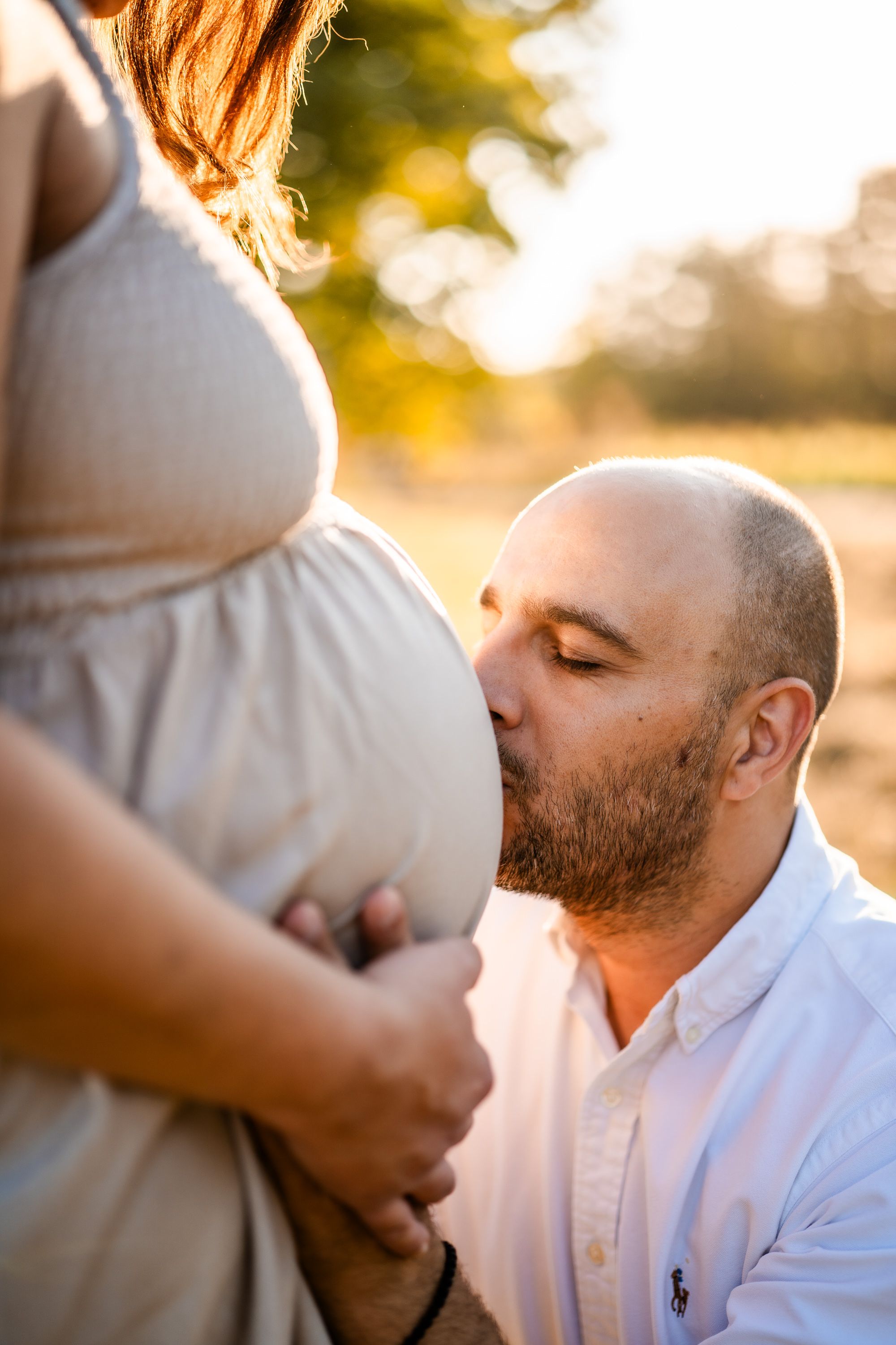Intimate maternity portrait showing couple in romantic pose with pink dress.