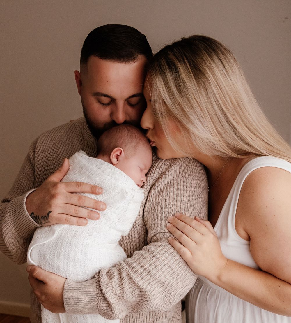 Intimate family portrait with newborn baby in neutral studio setting. Captured in a natural light studio in the blue mountains Sydney