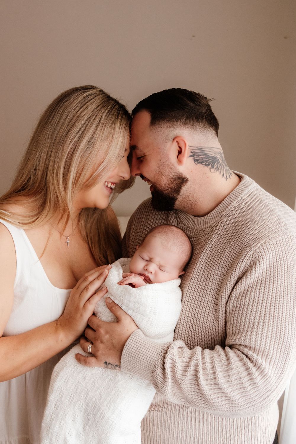 Parents sharing loving moments with their newborn baby against a neutral beige background. in a natural light studio in the blue mountains