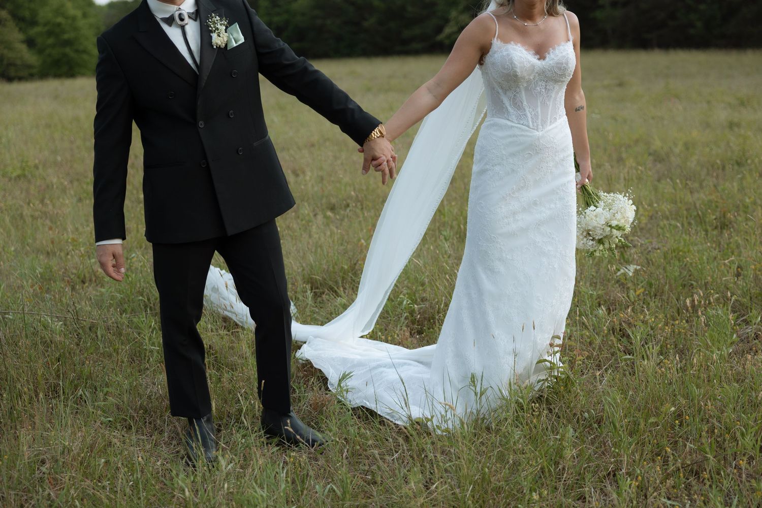 Playful wedding couple in garden with roses as bride feeds groom cake.