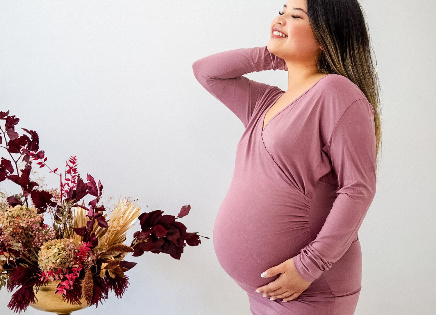 Pregnant woman in crop top and jeans relaxing with sunflowers.