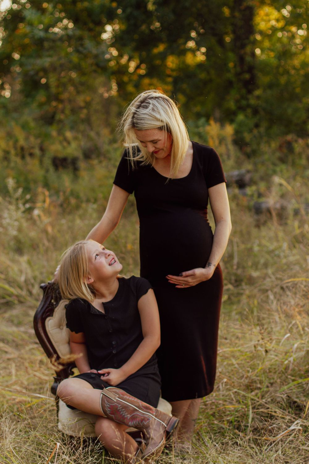 An expectant mother and her young daughter wearing matching black dresses on a fall day in Northeast Arkansas, by Delta Blossoms Photography