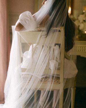 Artistic bridal photo featuring flowing white veil and wedding dress details.