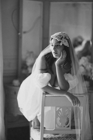 Vintage black and white photo of a seated figure in a wedding dress and veil.