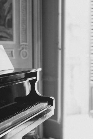 Side view of a black grand piano in an elegant room with natural light.