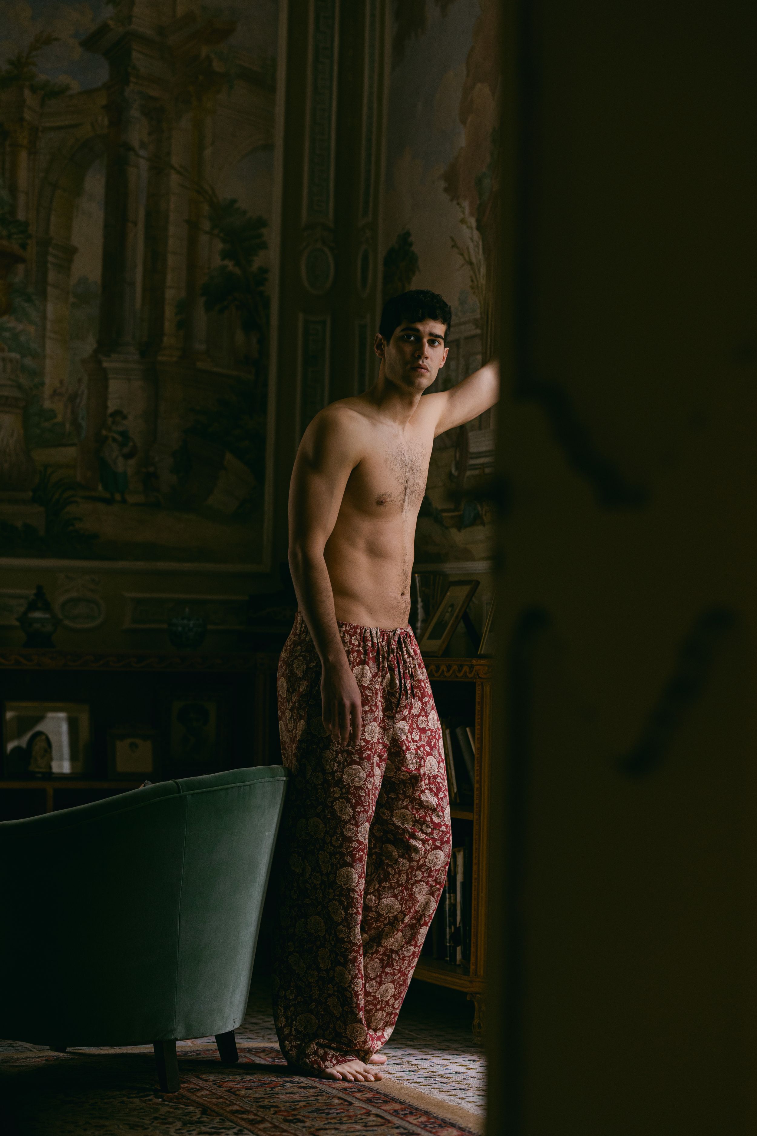 Artistic boudoir photo showing a person in red patterned pants against a vintage backdrop.