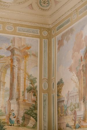 Detailed view of baroque-style ceiling with painted murals featuring classical architecture and figures.