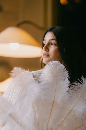 Artistic portrait with white feathers and warm lighting creating a dreamy atmosphere.