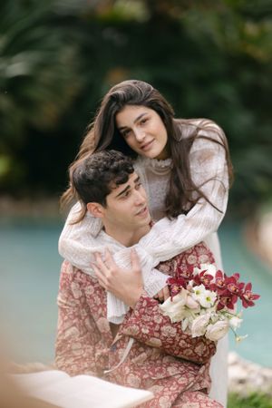 A couple in coordinating outfits sharing an intimate moment with flowers in a romantic outdoor setting.