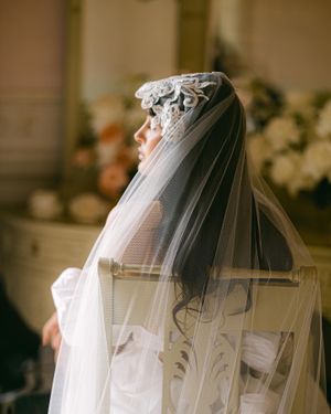 Side profile of a bridal veil with ornate lace detailing in soft natural light.