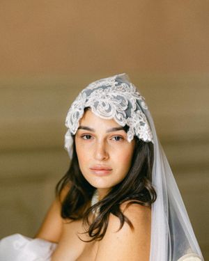 Bridal portrait highlighting delicate lace veil against warm neutral backdrop.