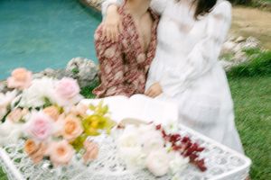 Dreamy motion-blurred photo of floral arrangements and wedding attire by water.