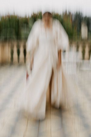 Artistic motion blur photo of figure in flowing white wedding dress.