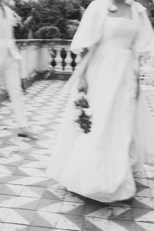 Black and white photo of flowing wedding dress on decorative tiled terrace.