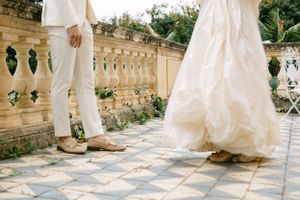 Wedding couple's feet and formal attire shown on ornate stone patio.