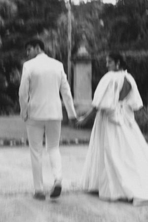 Artistic blurred black and white photo of newlyweds walking hand in hand outdoors.