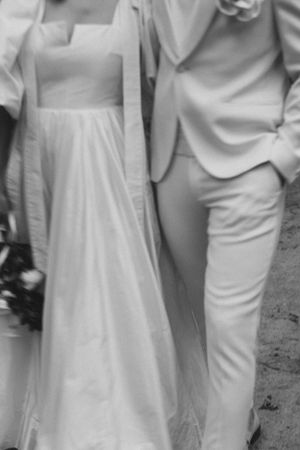 Black and white detail of wedding attire showing a white dress and suit.