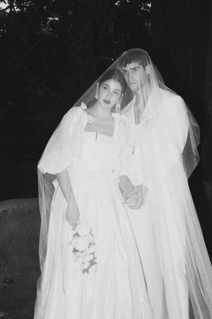 Ethereal black and white portrait of couple in matching white wedding attire.
